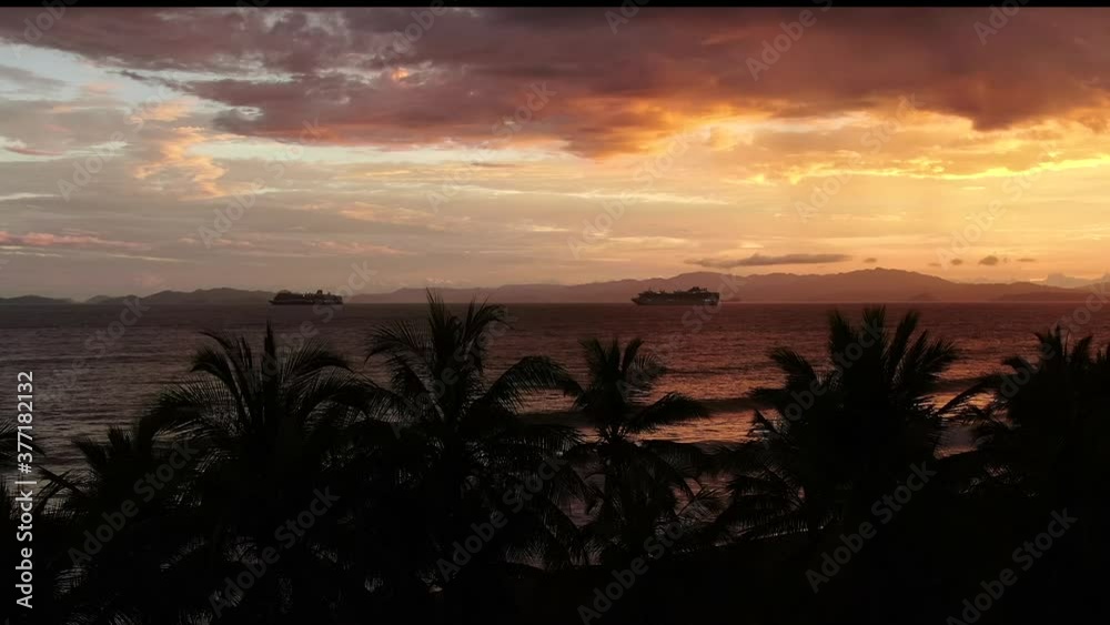 Beautiful cinematic aerial view of a great sunset in the middle of the ocean with a huge cruise ship and palm trees Beautiful cinematic aerial view of a great sunset in the middle of the ocean with a huge cruise ship and palm trees