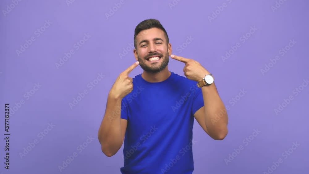 Young caucasian handsome man smiles, pointing mouth, concept of perfect teeth, white teeth, has a cheerful and jovial attitude Young caucasian handsome man smiles, pointing mouth, concept of perfect teeth, white teeth, has a cheerful and jovial attitude