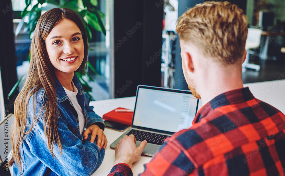 Fototapeta premium Portrait of cheerful Caucasian student smiling at camera during private lesson with male user for e learning software developing, collaborative meeting of young freelancers for doing distance job