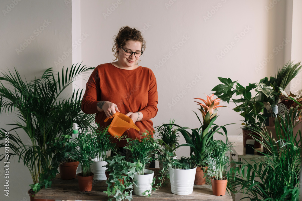 Young Smiling Girl Watering House Plants With Watering Can