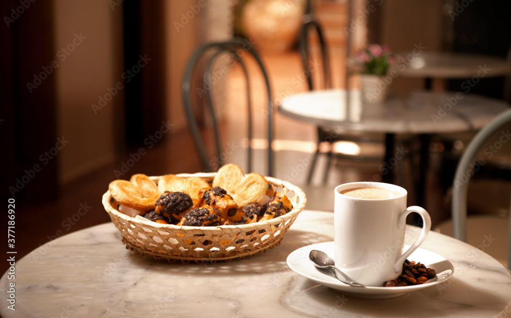 cup of coffee, on marble table, with pastries in wicker basket, cafeteria tables background cup of coffee, on marble table, with pastries in wicker basket, cafeteria tables background