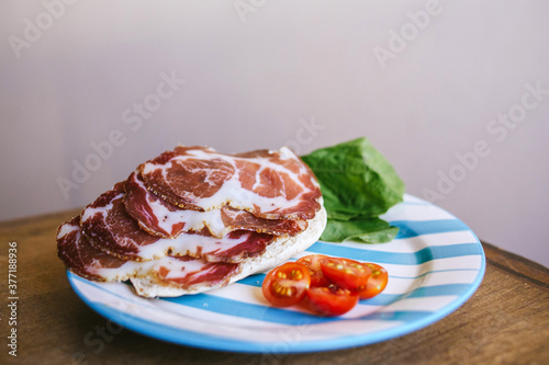 Rodajas de bondiola de cerdo en plato con rúcula y tomate cherry photo