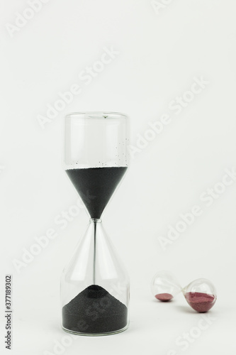 Vertical shot of two sand clocks made with glass on a white background. Time running and tempus fugit concept with copy space.