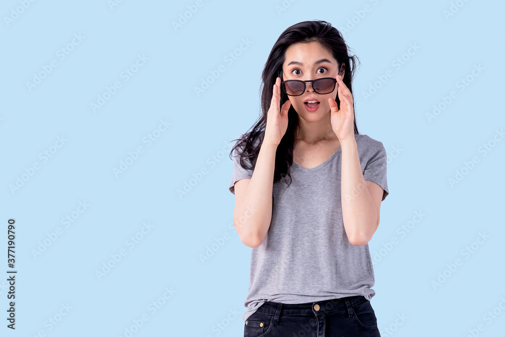 Portrait images of Asian attractive woman taking off her sunglasses and acting, excited expression on blue soft isolated background, to people and advertising concept. Portrait images of Asian attractive woman taking off her sunglasses and acting, excited expression on blue soft isolated background, to people and advertising concept.