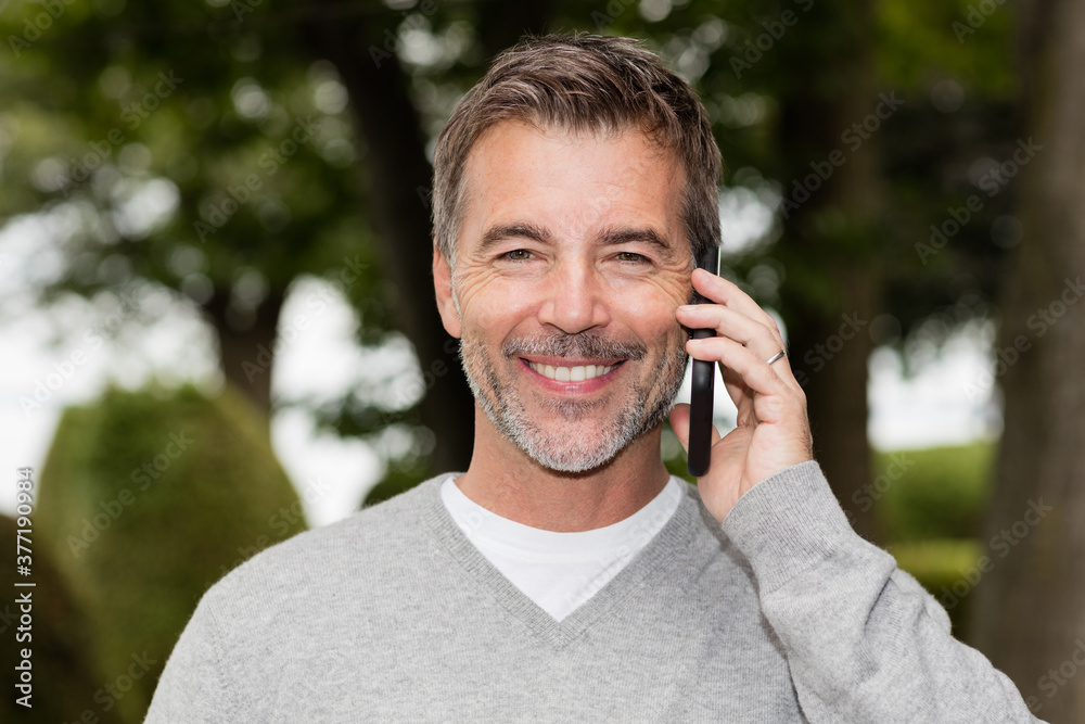 Handsome Mature Happy Man Smiling At The Camera. He is on a phone. Good news. Handsome Mature Happy Man Smiling At The Camera. He is on a phone. Good news.