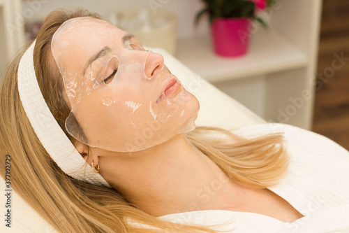young woman uses a hydrogel mask on her face. Procedure at the cosmetologist. Relax photo