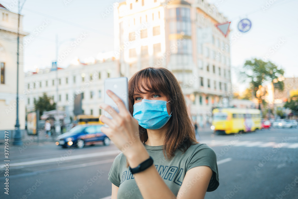 Young woman wearing medical face mask walks down city street