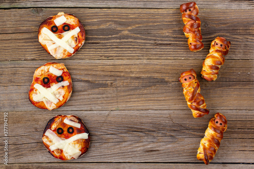 Mini pizza as mummy and Scary sausage mummies in dough for kids. Funny crazy Halloween food for children