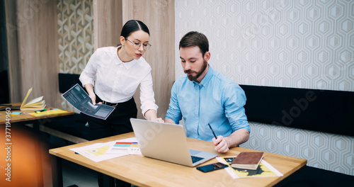 Young manager supporting colleague with work on laptop