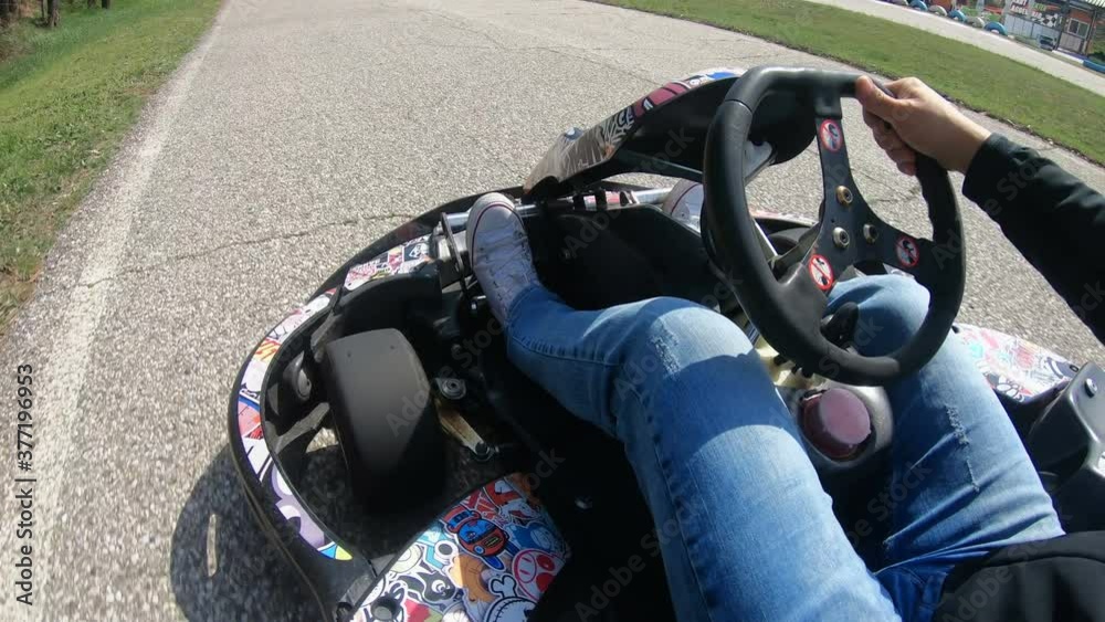 POV of arms and legs driving fast go-cart around the raceway during competition on the curvy raceway