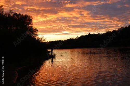Beautiful blazing sunset landscape above river and orange sky in evening © alexmak