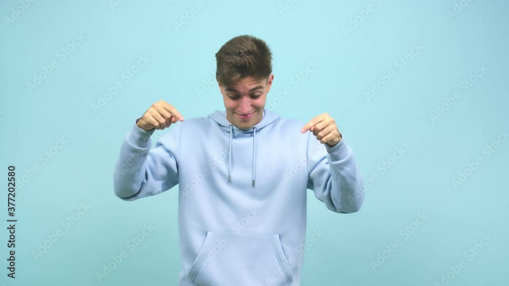 Young caucasian student man pointing down, smiling surprised presenting something, natural and casual Young caucasian student man pointing down, smiling surprised presenting something, natural and casual