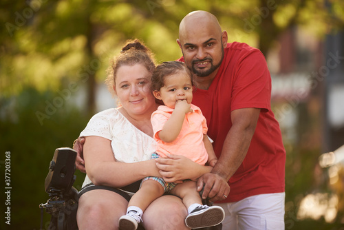 Portrait of young inter racial family, woman is disabled and in wheelchair.