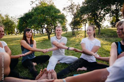A group of people do yoga in a circle in the open air during sunset. Healthy lifestyle, meditation and Wellness