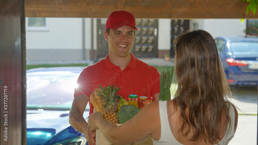 Φωτογραφία CLOSE UP: Happy delivery guy hands Caucasian woman her order of organic produce