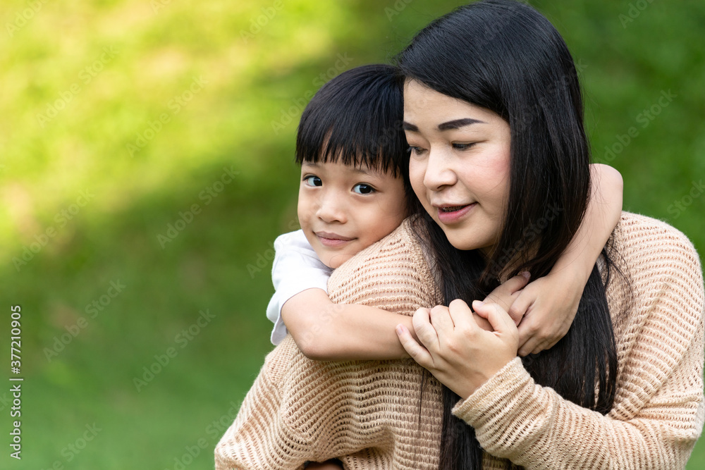 Portrait beautiful mother and child happily hugged in park. Asian family mom and child are hugging and looking at the camera, cute and warm. Portrait beautiful mother and child happily hugged in park. Asian family mom and child are hugging and looking at the camera, cute and warm.