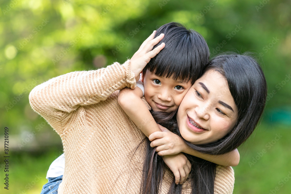 Portrait beautiful mother and child happily hugged in park. Asian family mom and child are hugging and looking at the camera, cute and warm. Portrait beautiful mother and child happily hugged in park. Asian family mom and child are hugging and looking at the camera, cute and warm.