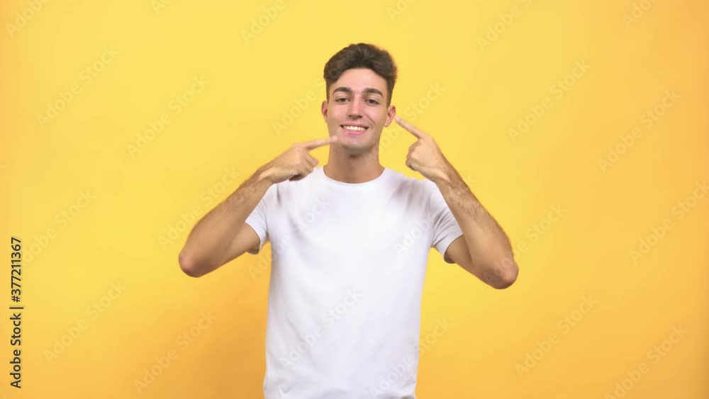 Young caucasian student man smiles, pointing mouth, concept of perfect teeth, white teeth, has a cheerful and jovial attitude Young caucasian student man smiles, pointing mouth, concept of perfect teeth, white teeth, has a cheerful and jovial attitude