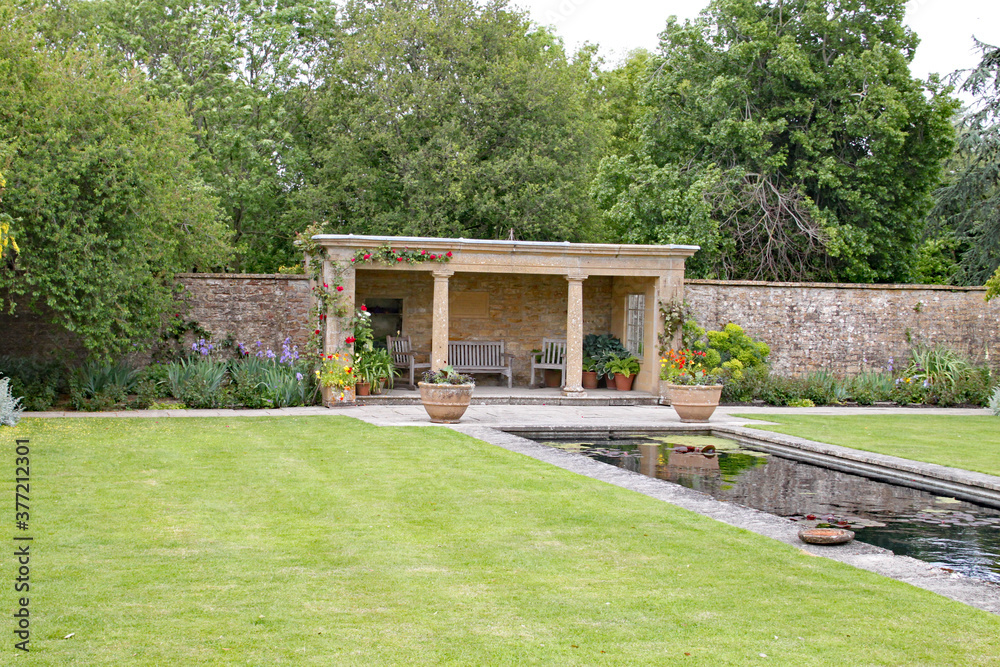 Covered seating area by an ornamental pond in an English country garden
