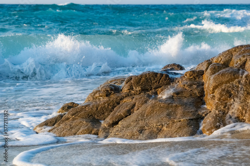 Waves breaking behind rocks in thebeach of Mesakti, Mediterranean Sea in the Aegean Island of Ikaria in Greece at the evening photo
