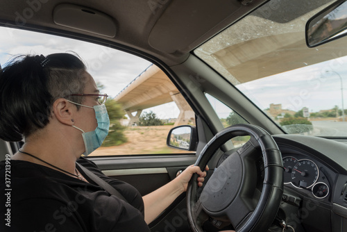 Woman driving a vehicle with a protective mask.