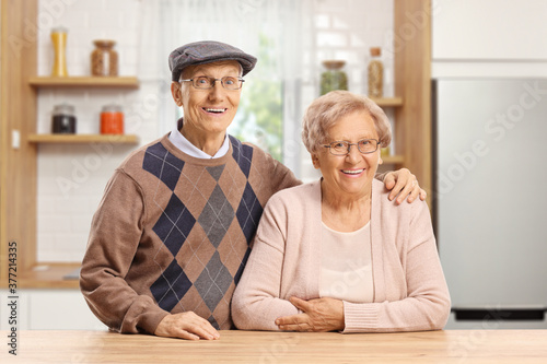 Elderly couple standing in a kitchen behind a wooden table