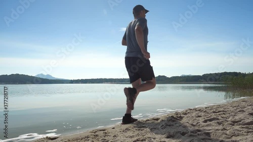 Single man running workout. Daily excercise run near summer lake. Training and working out in  morning sun.  Slow motion