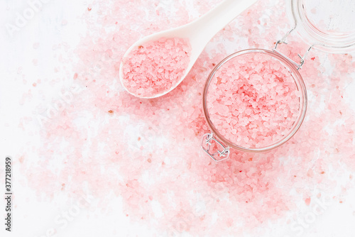Pink bath salt in a glass jar on pink bath salt background. Spa concept. Selective focus