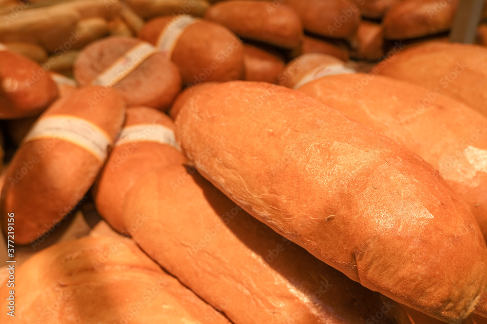 A lot of freshly baked breads with a golden crust in the tray, a loaf of bread close-up A lot of freshly baked breads with a golden crust in the tray, a loaf of bread close-up