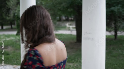 back view young beautiful woman in summer Park walking and talking on a mobile phone