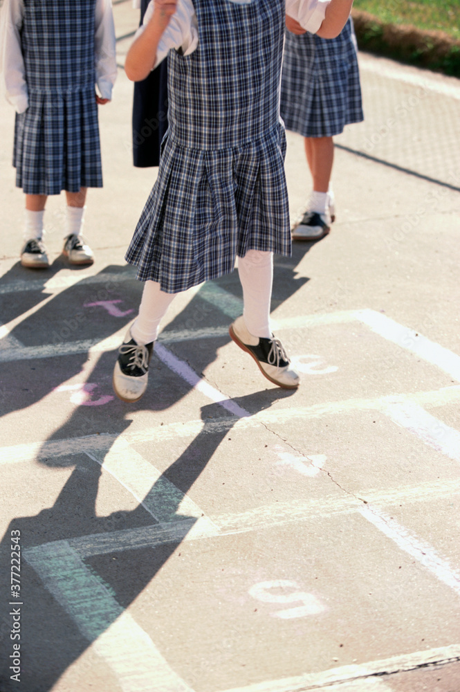 Girls in school uniforms playing hopscotch Girls in school uniforms playing hopscotch