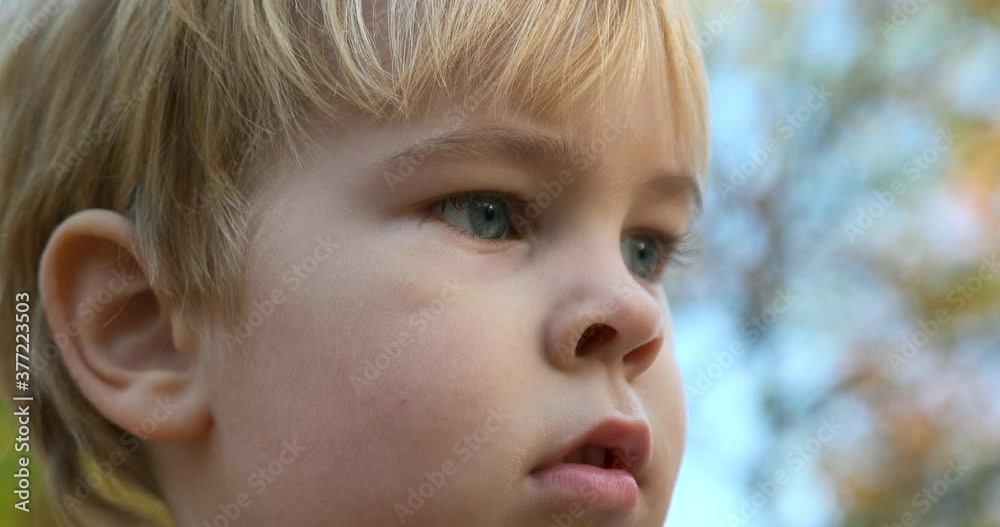 Close-up Sad Child Face Emotion. Cute Upset Serious Boy Stands Thinking Outdoors Close-up Sad Child Face Emotion. Cute Upset Serious Boy Stands Thinking Outdoors