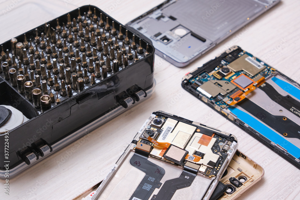 a close-up of a set of screwdriver bits in a black box, gloves, broken smartphones and a set of tools for replacing the glass of a phone and tablet a close-up of a set of screwdriver bits in a black box, gloves, broken smartphones and a set of tools for replacing the glass of a phone and tablet