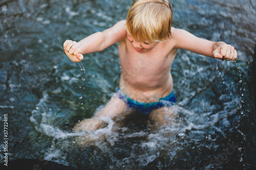 Boy swimming in river with hands and water droplets in focus. Summer in central New South Wales, Australia