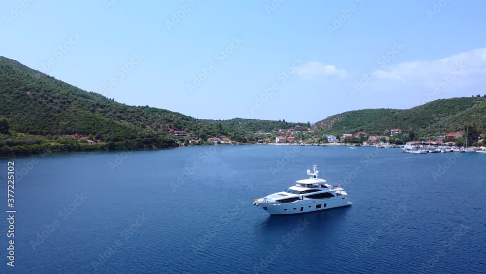 Expensive luxury yacht standing in the bay surrounded with hills and touristic resort. Aerial view Expensive luxury yacht standing in the bay surrounded with hills and touristic resort. Aerial view