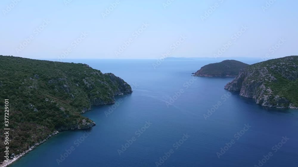 Aerial view of bay with passage between to hills covered by pine trees and open blue sea behind. Aerial view of bay with passage between to hills covered by pine trees and open blue sea behind.