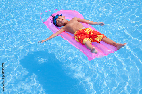 浮き輪でプールに浮かぶ水着姿の男の子