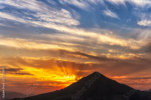 Sun Rays At Sunset, Clouds, behind Silhouetted Mountain 