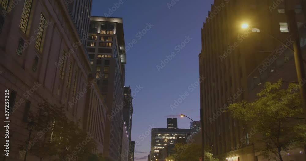 Montreal, QC, Canada - April 15, 2017: Worm eye view of Downtown Skyscrapers with dusk blue sky background, driving on Saint Antoine Street at night. Montreal, QC, Canada - April 15, 2017: Worm eye view of Downtown Skyscrapers with dusk blue sky background, driving on Saint Antoine Street at night.