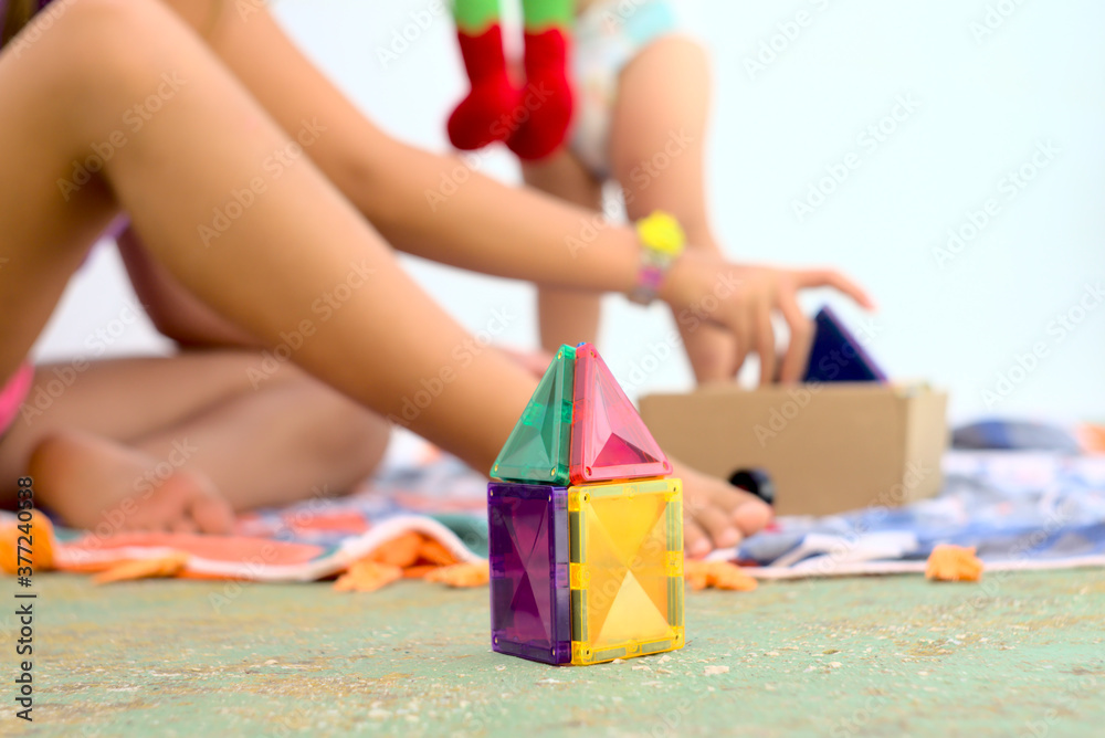 Málaga, Spain. Children playing a colorful plastic magnet construction game on a piece of fabric on the floor. Málaga, Spain. Children playing a colorful plastic magnet construction game on a piece of fabric on the floor.