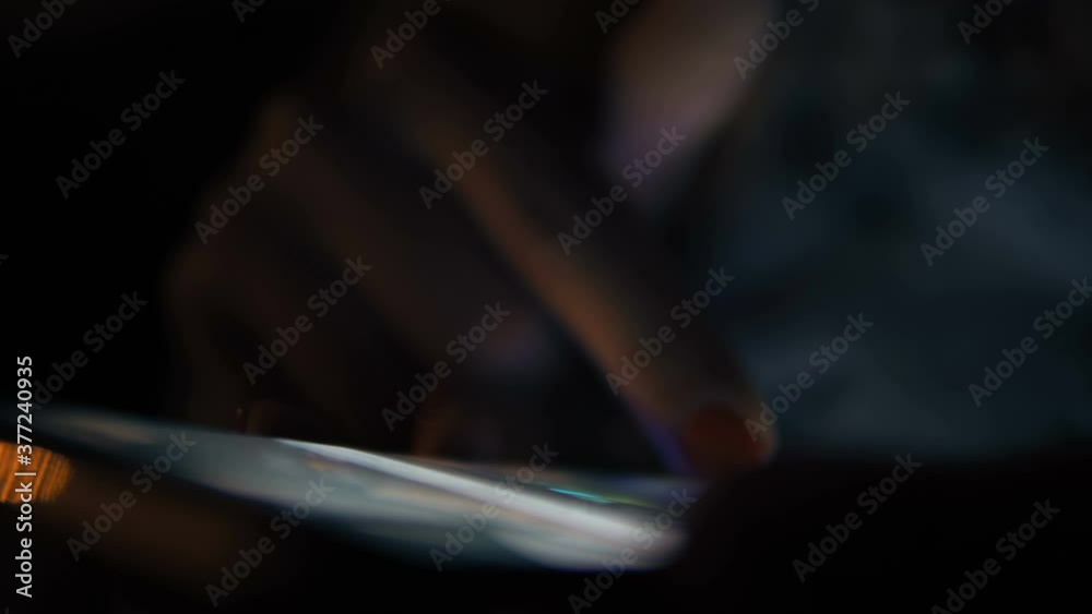 Woman using interactive touchscreen display in modern smartphone. Evening time, lowlight. Education and entertainment concept. Close up shot Woman using interactive touchscreen display in modern smartphone. Evening time, lowlight. Education and entertainment concept. Close up shot