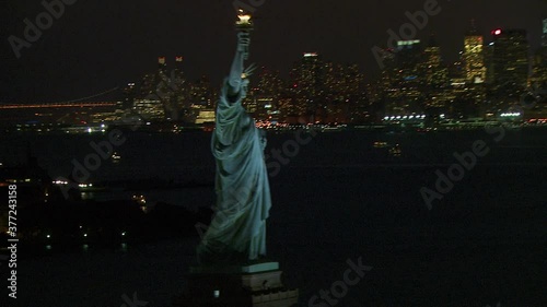 Pivoting around Statue of Liberty revealing NYC at night