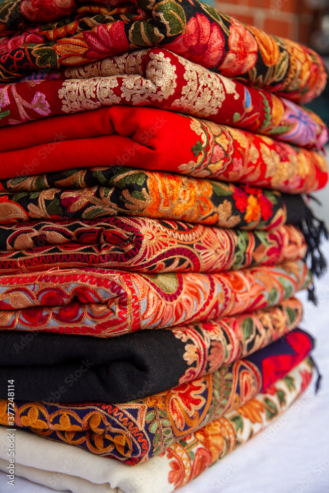 Kashmiri embroidered wool shawls folded in a stack. 
