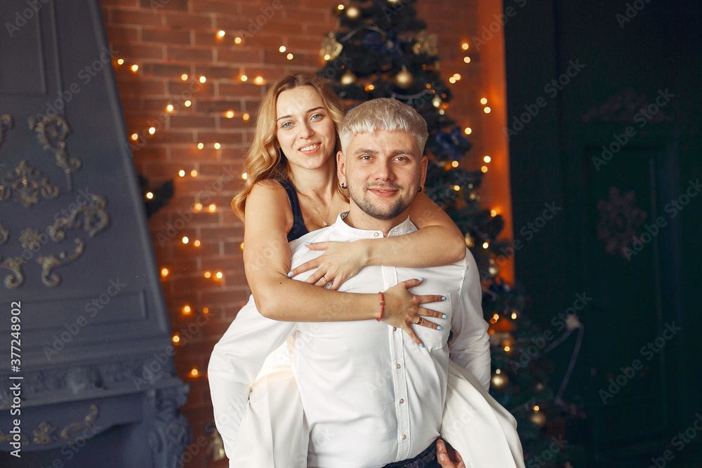 Couple near christmas tree. Lady in a white sweater. Family in a christmas decorations.
