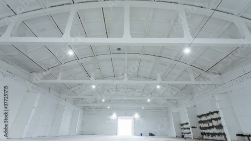 The interior of a huge industrial warehouse made of white bricks with a high ceiling for storing goods. 