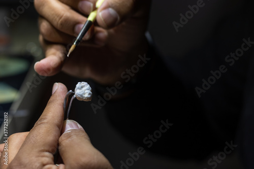 Close up and side view of a man working a prosthetic tooth