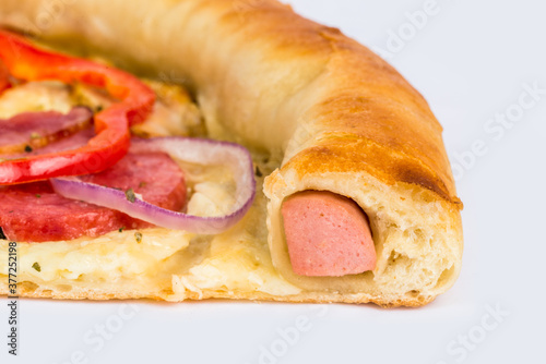 Slice of pizza on a white plate with a sausage rim