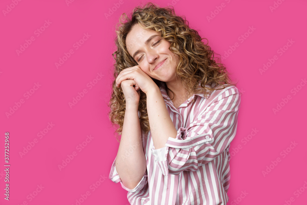 Happy contented woman holds her hands together near the face.