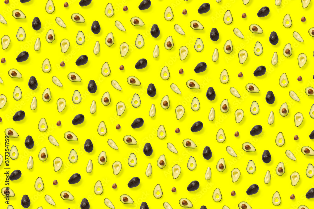 Avocado. Background made from isolated Avocado pieces on yellow background. Flat lay of fresh ripe avocados and avacado pieces. Avocado. Background made from isolated Avocado pieces on yellow background. Flat lay of fresh ripe avocados and avacado pieces.