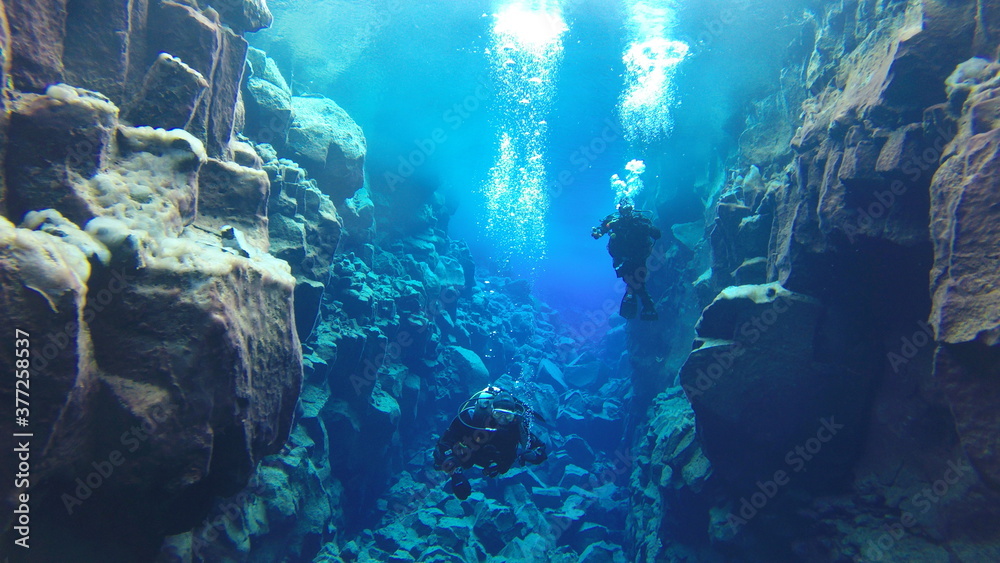 bubbles rising to reflective glacial water underwater surface whilst scuba diving in iceland